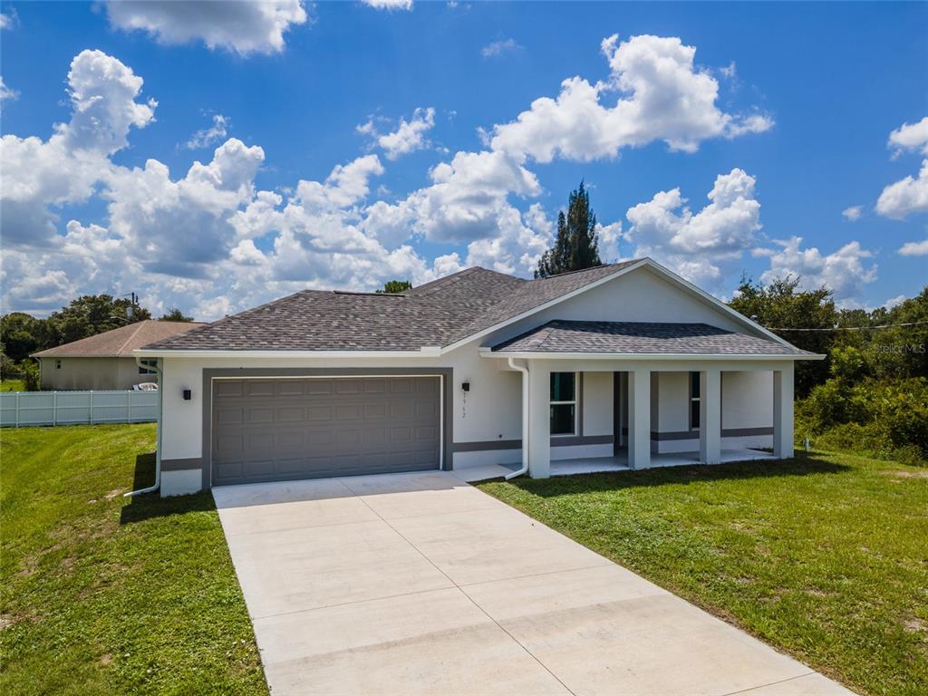 A single-story house with a white exterior, gray garage door, and a concrete driveway — 1962 LEGHORN STREET, LEHIGH ACRES, FL