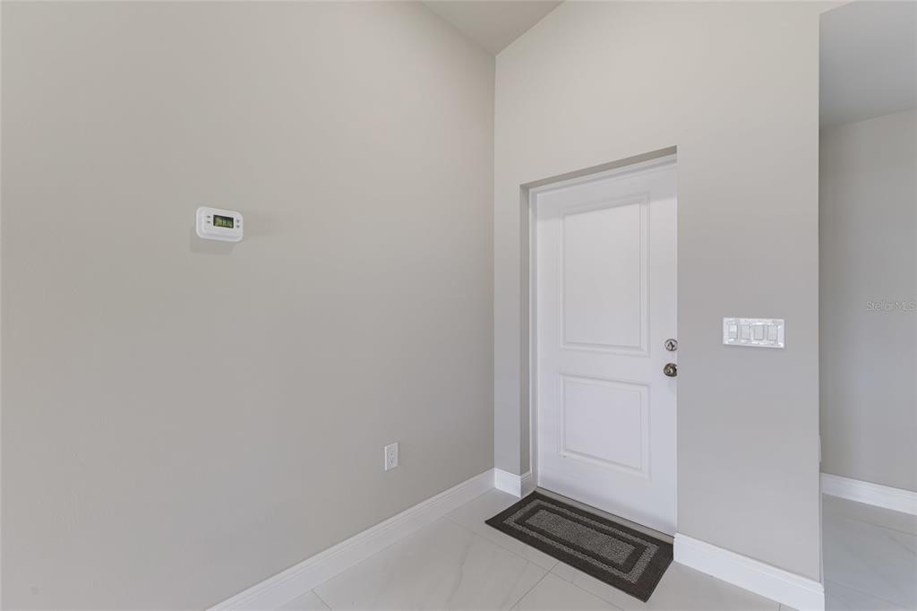 A white door with a dark mat sits in a room with light walls — 1962 LEGHORN STREET, LEHIGH ACRES, FL