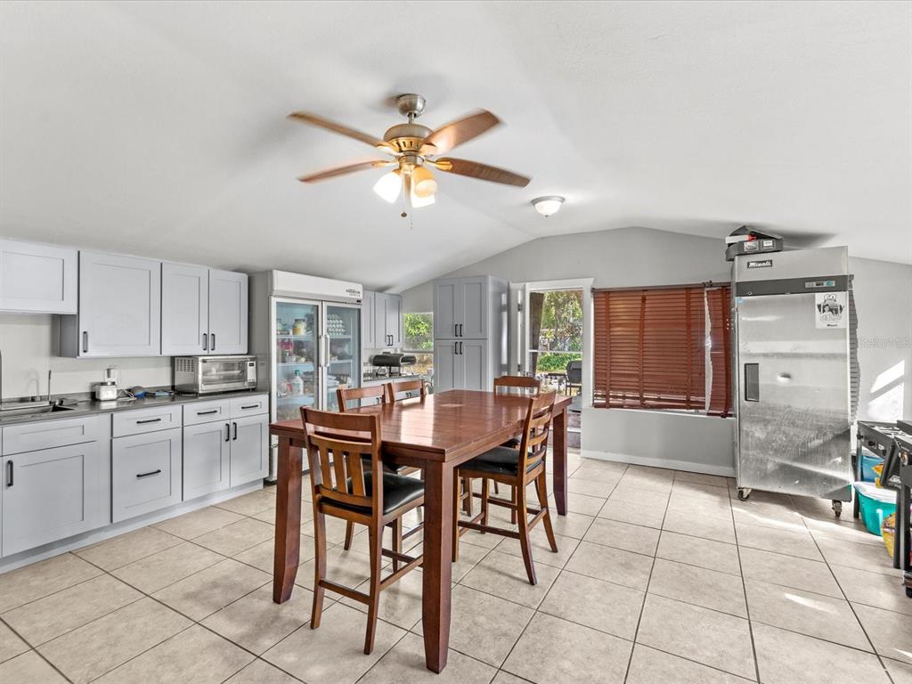 A kitchen and dining area with light gray cabinets, tile flooring, and a wooden table — 12218 ELKTON AVENUE, HUDSON, FL