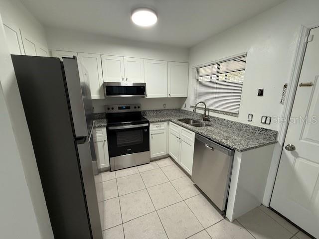 A kitchen features white cabinets, granite countertops, stainless steel appliances, and light-colored tile flooring — 133 GARDEN DRIVE, WINTER SPRINGS, FL