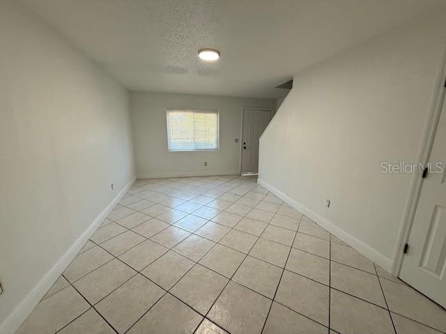 An empty room features white walls, a window, and light-colored diagonal floor tiles — 133 GARDEN DRIVE, WINTER SPRINGS, FL