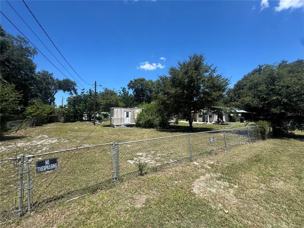 A fenced, grassy lot features a small shed and a house in the background — 2795 JANIE LANE, BARTOW, FL