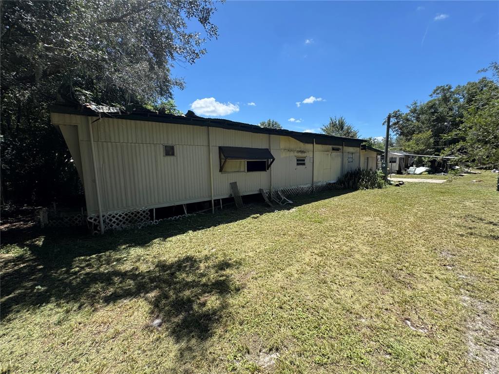 The exterior of a weathered, single-wide mobile home sits on a grassy lot — 2795 JANIE LANE, BARTOW, FL