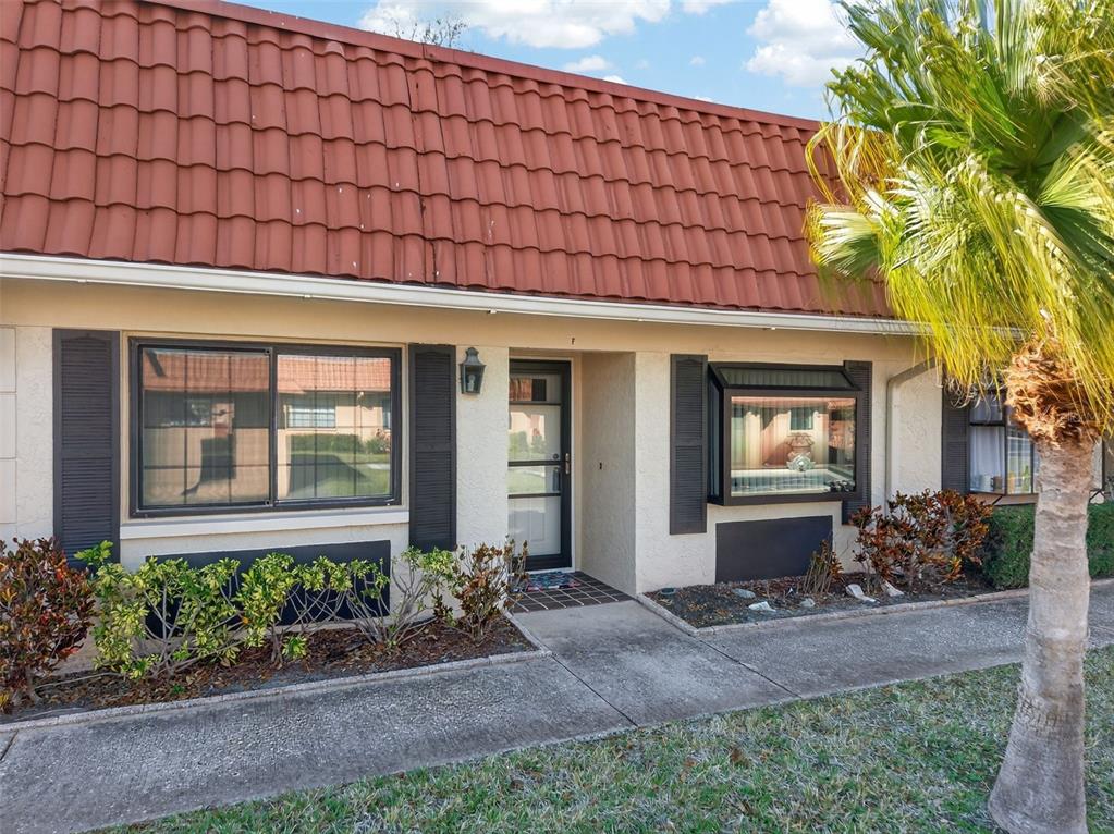 A one-story residential building features a red tile roof, stucco walls, and a front entrance — 19029 US HIGHWAY 19 N UNIT 18F, CLEARWATER, FL