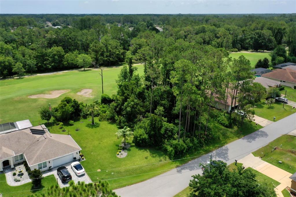 An aerial view shows a vacant wooded lot situated between two houses and a golf course — 93 EDWARD DRIVE, PALM COAST, FL