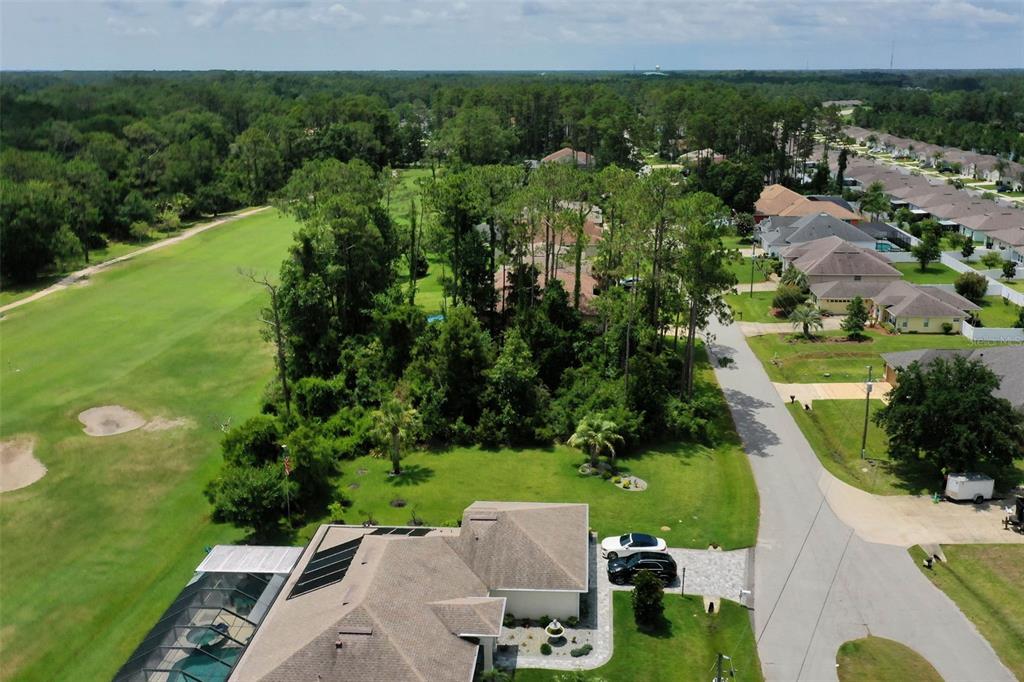 An aerial view shows a house with a pool cage next to a golf course — 93 EDWARD DRIVE, PALM COAST, FL