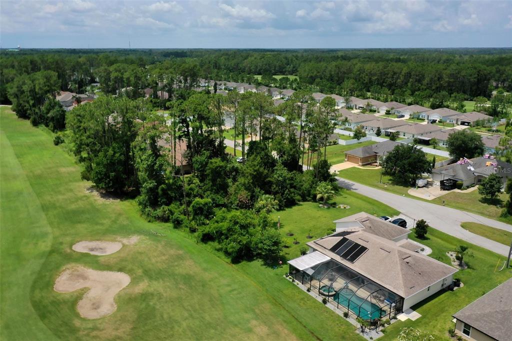 An aerial view shows a house with a pool and solar panels near a golf course — 93 EDWARD DRIVE, PALM COAST, FL