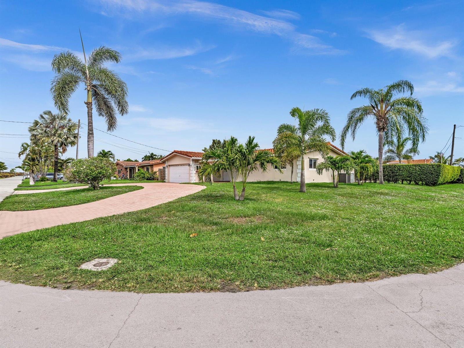 A single-story house with a paved driveway and palm trees sits on a grassy lot — 641 SE 11th Street, Pompano Beach FL 33060, POMPANO BEACH, FL