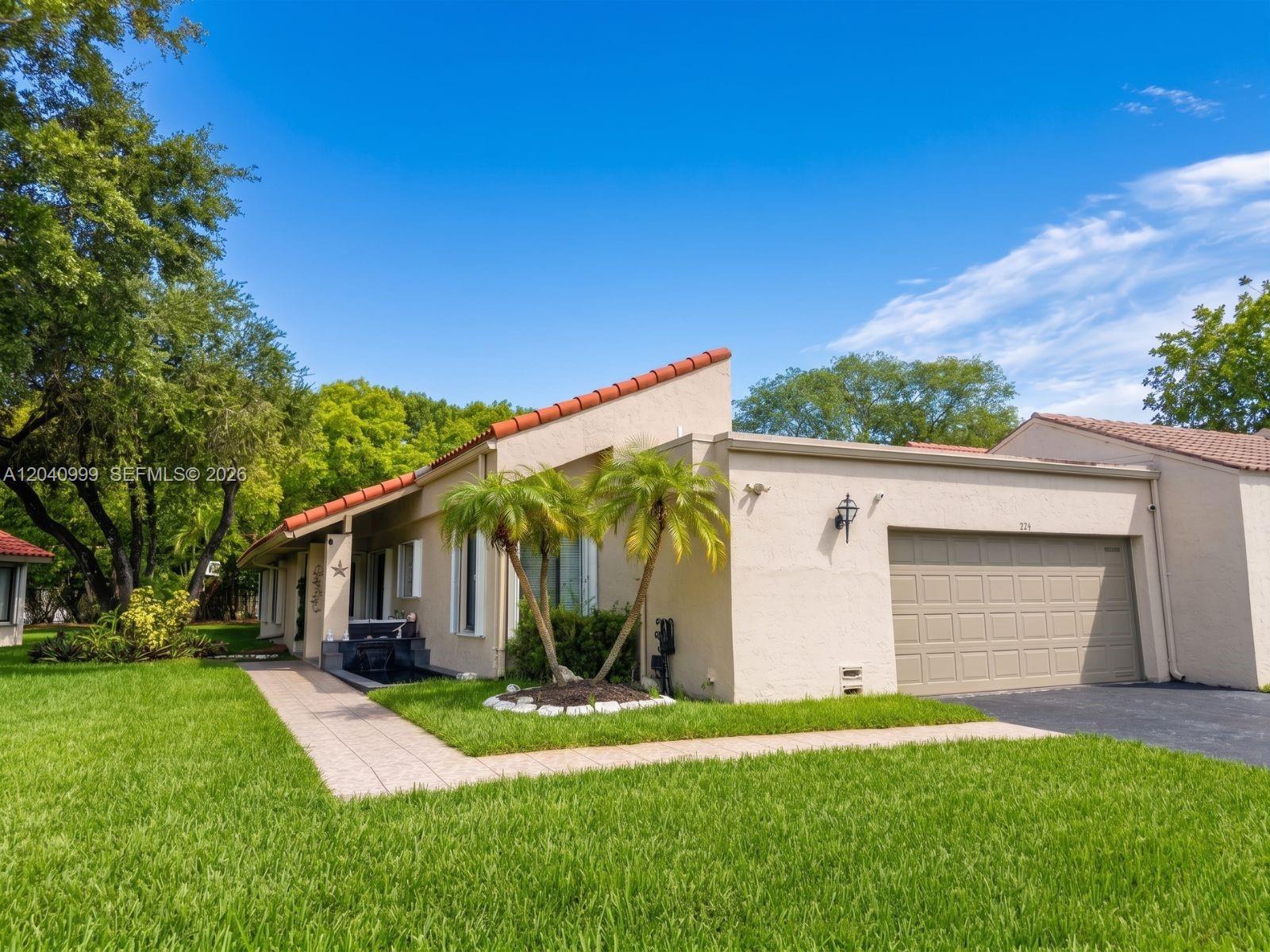 A single-story house with a tan stucco exterior, a tiled roof, and a two-car garage — 324 Patio Village Ter, Weston FL 33326, WESTON, FL
