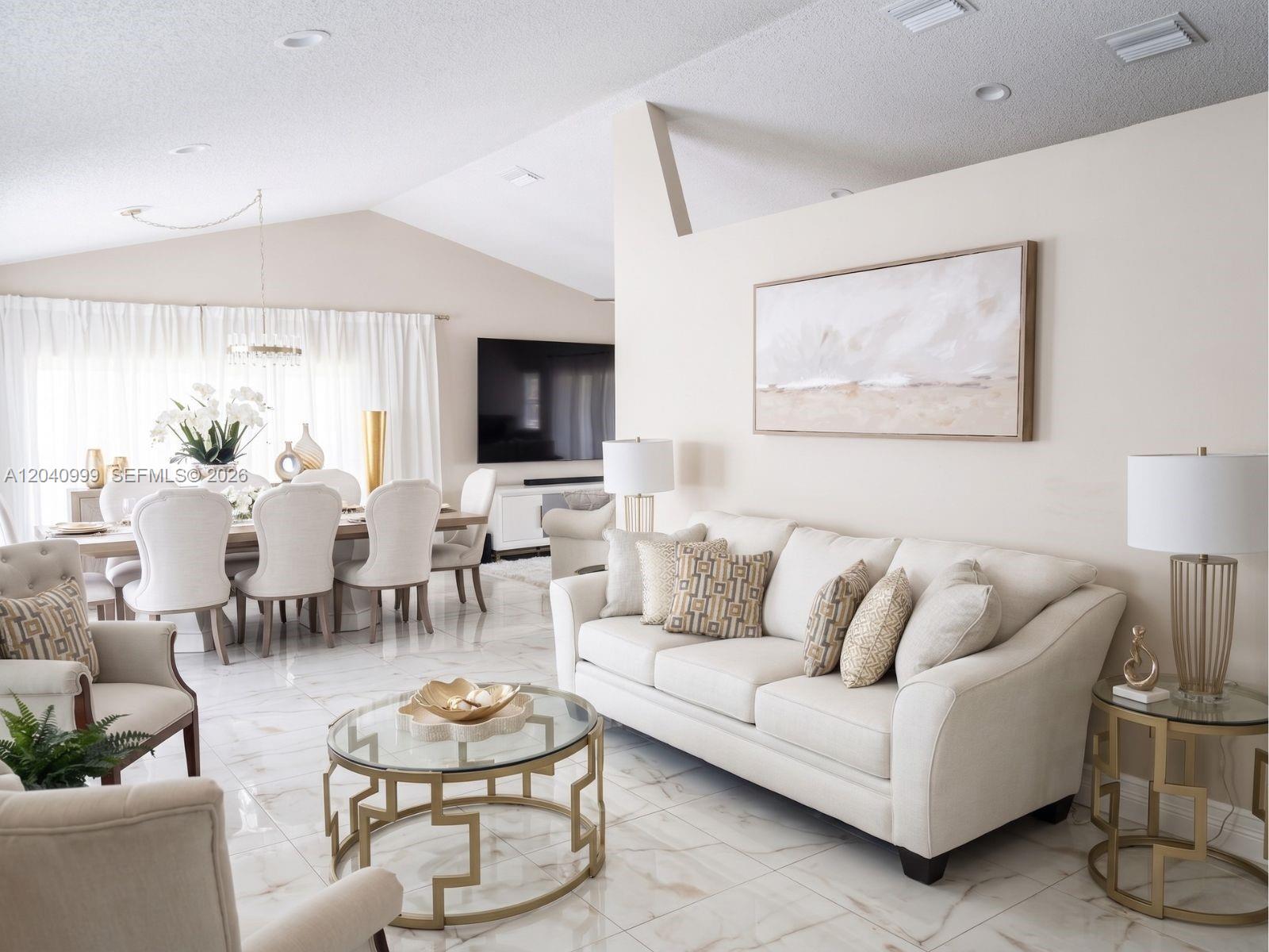 A bright, open-concept living and dining area features cream-colored furniture, gold accents, and marble flooring — 324 Patio Village Ter, Weston FL 33326, WESTON, FL