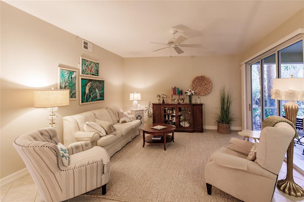 A living room features a sofa, two armchairs, a coffee table, and a sliding glass door — 1878 TARPON BAY DRIVE S UNIT 102, NAPLES, FL