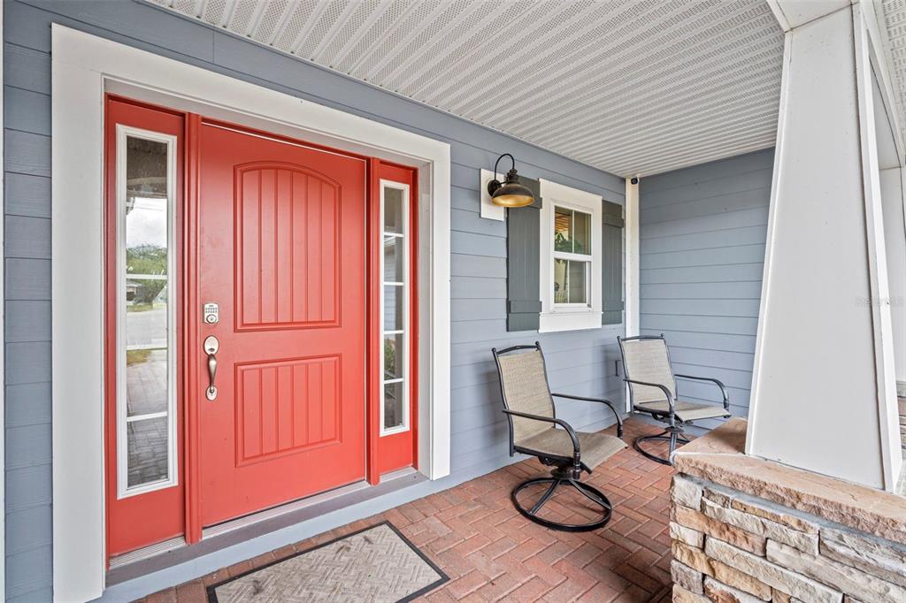 A covered front porch features a red door, gray siding, and two outdoor chairs — 510 CODY ALLEN COURT, ST CLOUD, FL