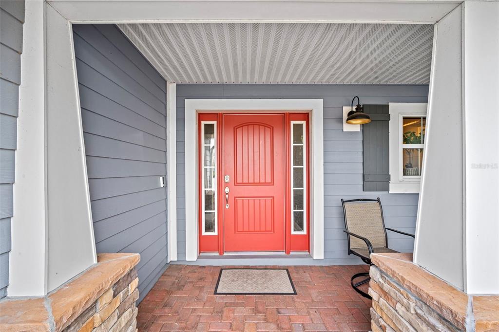 A red front door with sidelights sits on a brick porch with gray siding — 510 CODY ALLEN COURT, ST CLOUD, FL