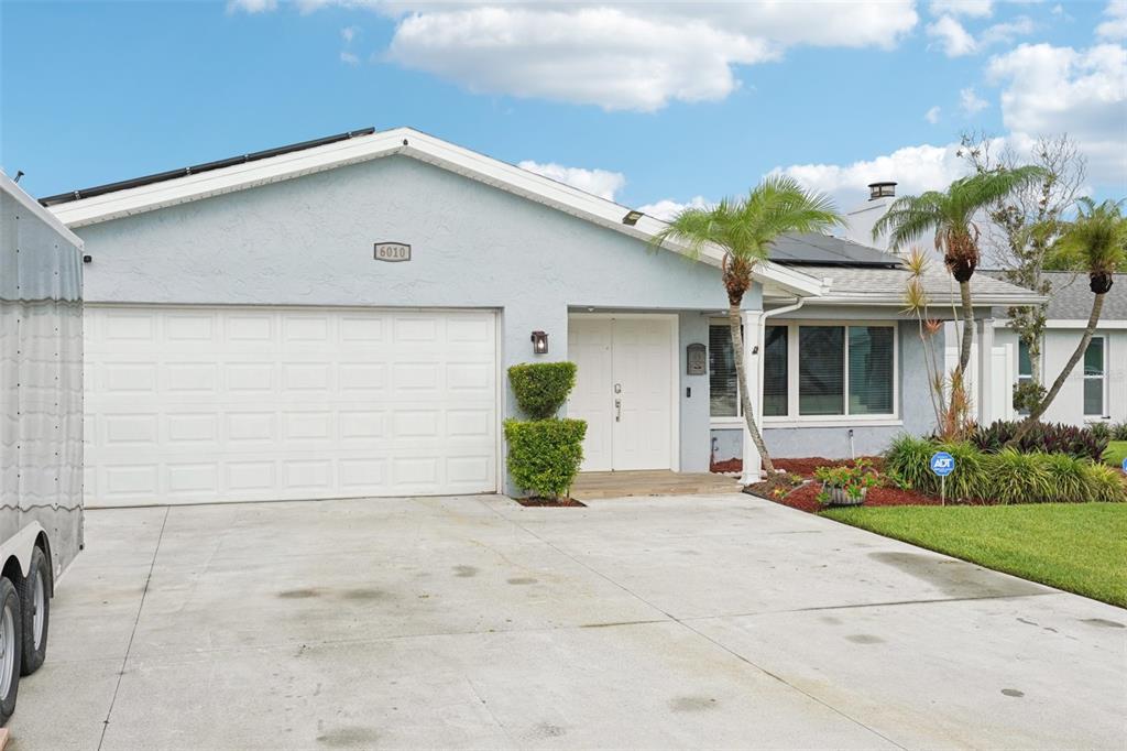 A light blue single-story house features a white garage door and a double front door — 6010 BAYOU GRANDE BOULEVARD NE, ST PETERSBURG, FL