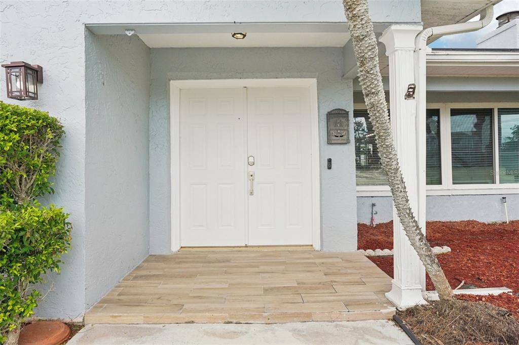 A white double front door with a tiled porch and a columned entryway — 6010 BAYOU GRANDE BOULEVARD NE, ST PETERSBURG, FL