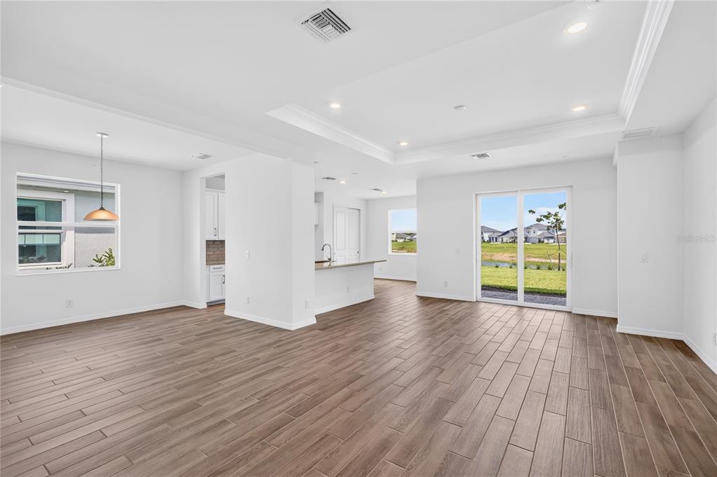 An open-concept living and dining area features white walls, recessed lighting, and wood-look tile flooring — 15766 ELINA SKY DRIVE, PUNTA GORDA, FL