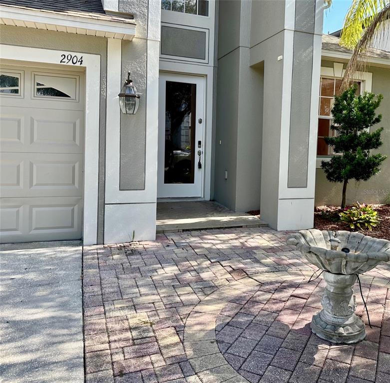 The exterior of a house features a paved walkway, a front door, and a birdbath — 2904 TRINITY COTTAGE DRIVE, LAND O LAKES, FL