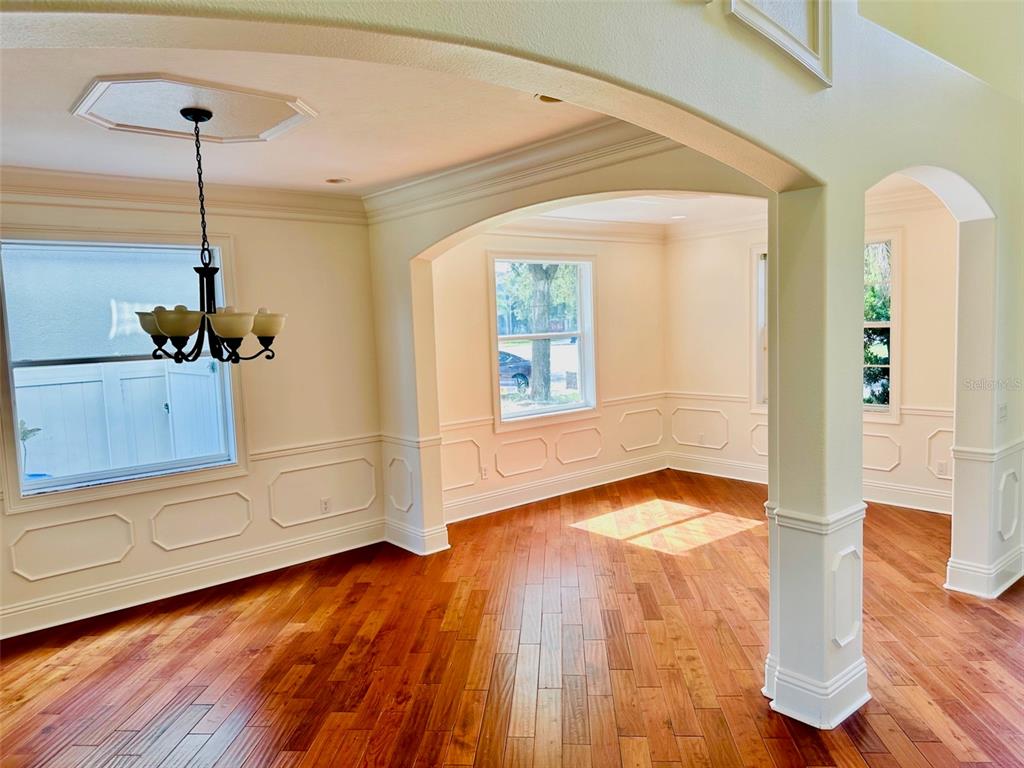 An empty dining room features hardwood floors, white wainscoting, and a black chandelier — 2904 TRINITY COTTAGE DRIVE, LAND O LAKES, FL