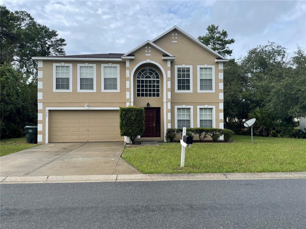 A two-story tan house with white trim, a two-car garage, and a front entryway — 5064 SPANISH OAKS BOULEVARD, LAKELAND, FL