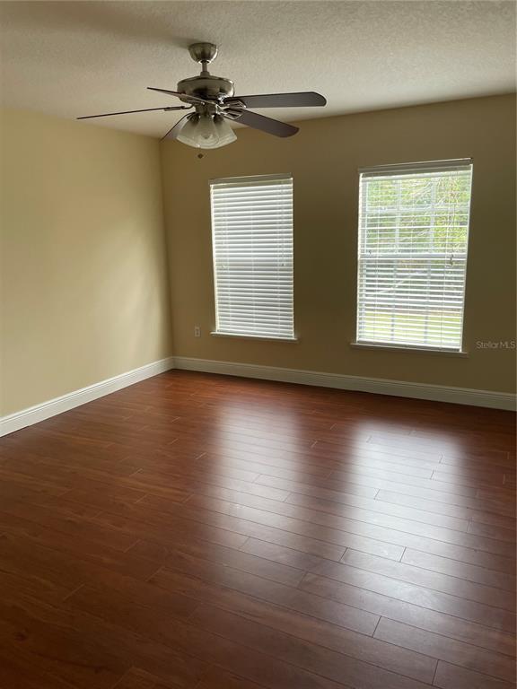 An empty bedroom features wood-look flooring, two windows with blinds, and a ceiling fan — 5064 SPANISH OAKS BOULEVARD, LAKELAND, FL