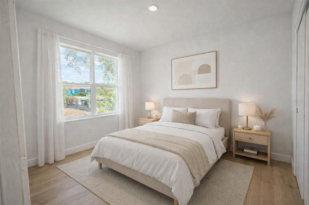 A bright bedroom features a queen bed, two nightstands, a window, and light wood flooring — 4517 AMERICA STREET, ORLANDO, FL