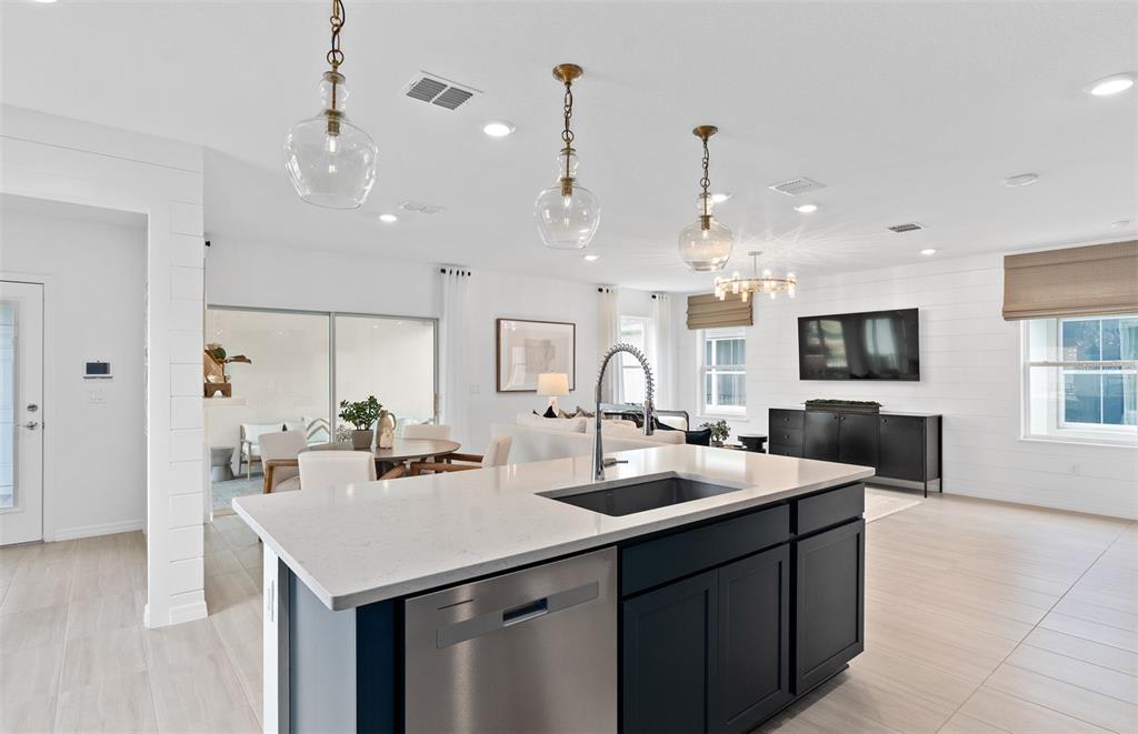 A kitchen island with a stainless steel dishwasher faces a living area with white shiplap — 5093 STARLING BIRD LANE, ST CLOUD, FL