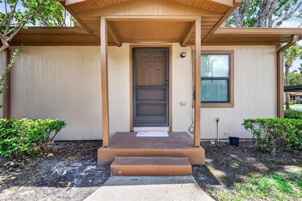 A tan exterior wall with a brown front door, screen door, and concrete porch steps — 304 ERON WAY UNIT 2, WINTER GARDEN, FL