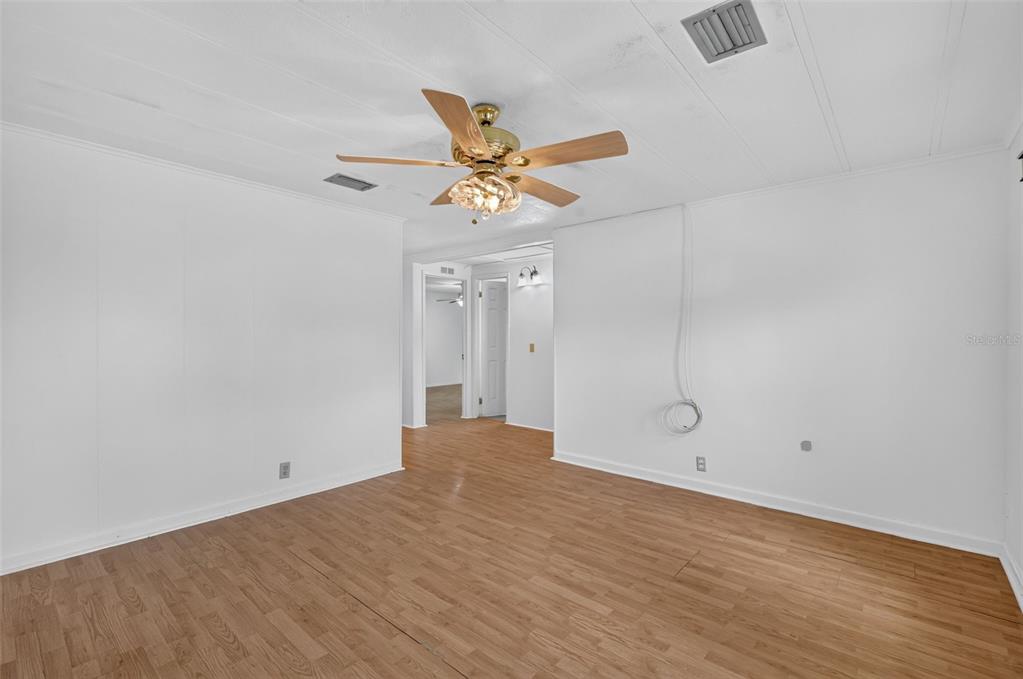 A bright, empty room features white walls, wood-look flooring, and a ceiling fan — 304 ERON WAY UNIT 2, WINTER GARDEN, FL