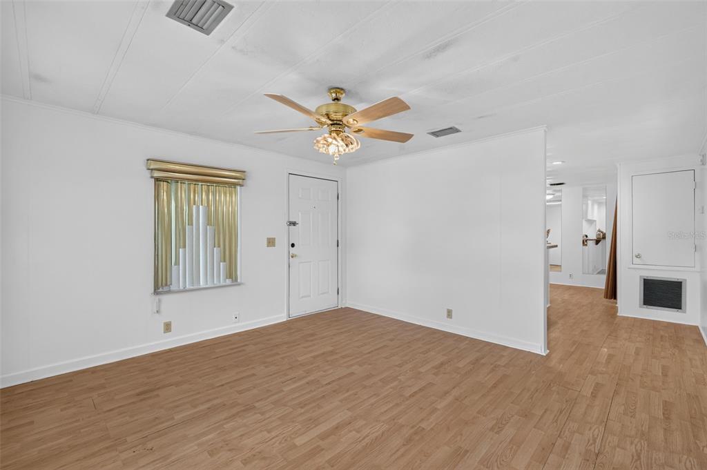 A living room with white walls, wood-look flooring, a ceiling fan, and a front door — 304 ERON WAY UNIT 2, WINTER GARDEN, FL
