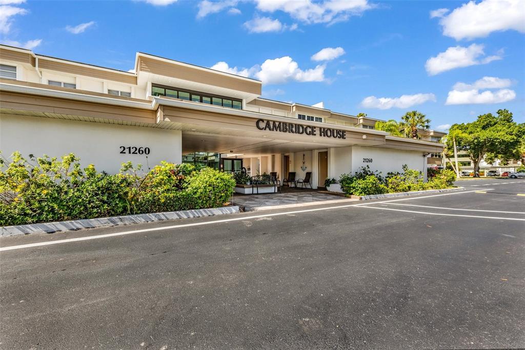 The exterior of a low-rise apartment building features a covered entrance and parking lot — 21260 BRINSON AVENUE UNIT 303, PORT CHARLOTTE, FL