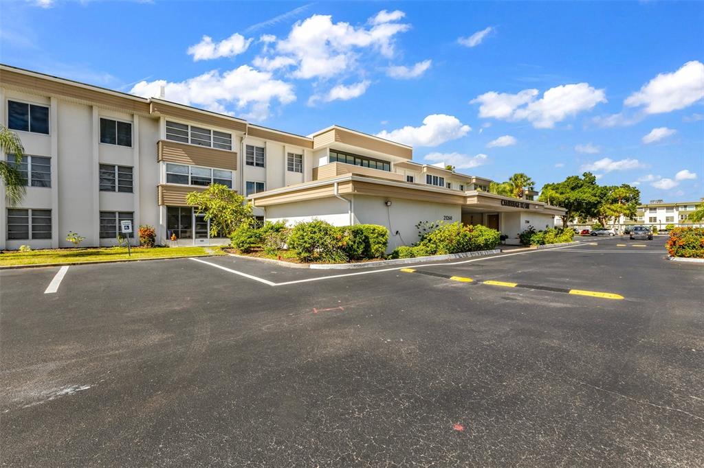 A multi-story apartment building with a parking lot in the foreground under a blue sky — 21260 BRINSON AVENUE UNIT 303, PORT CHARLOTTE, FL