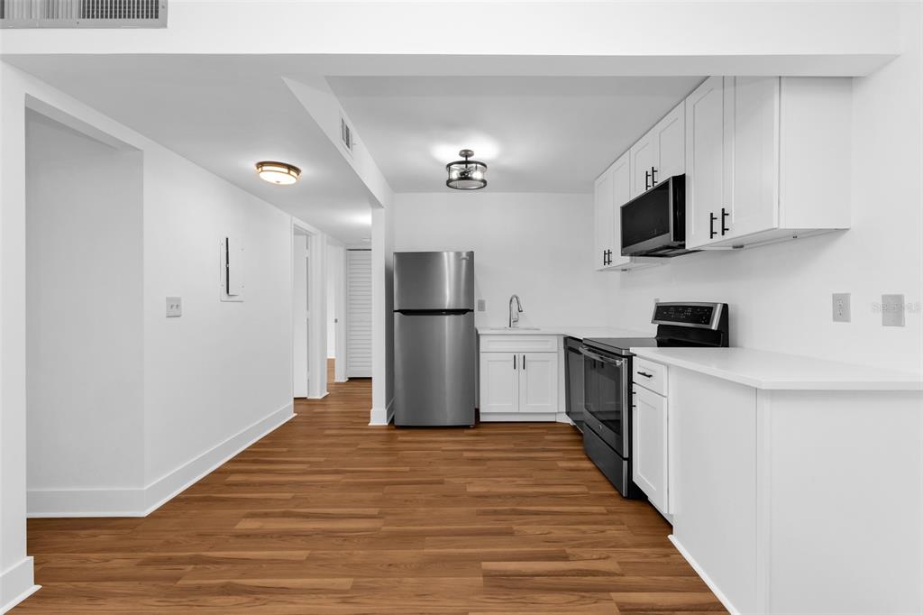 A kitchen features white cabinets, stainless steel appliances, and wood-look flooring — 21260 BRINSON AVENUE UNIT 303, PORT CHARLOTTE, FL