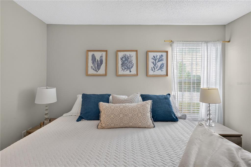 A bedroom features a bed with blue and patterned pillows beneath three framed botanical prints — 706 LOCKBREEZE DRIVE, DAVENPORT, FL