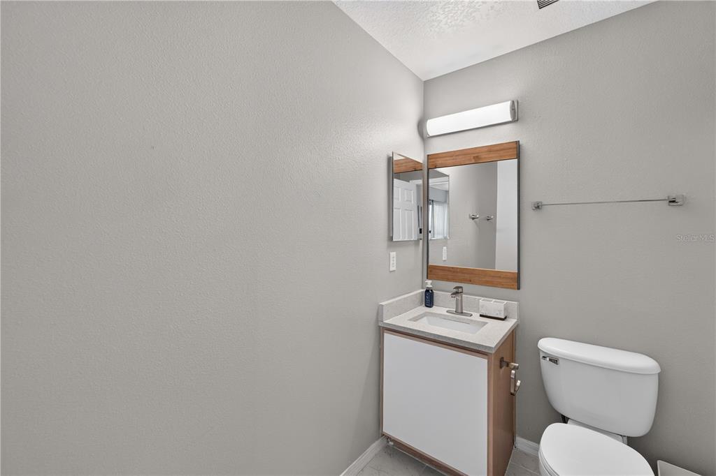 A small bathroom features a vanity with a light countertop, a mirror, and a toilet — 706 LOCKBREEZE DRIVE, DAVENPORT, FL
