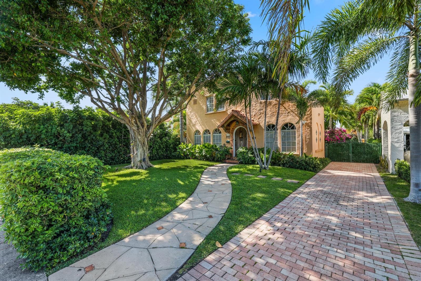 A two-story stucco house with a stone walkway, brick driveway, and large mature trees — 325 Greymon Drive, West Palm Beach FL 33405, WEST PALM BEACH, FL