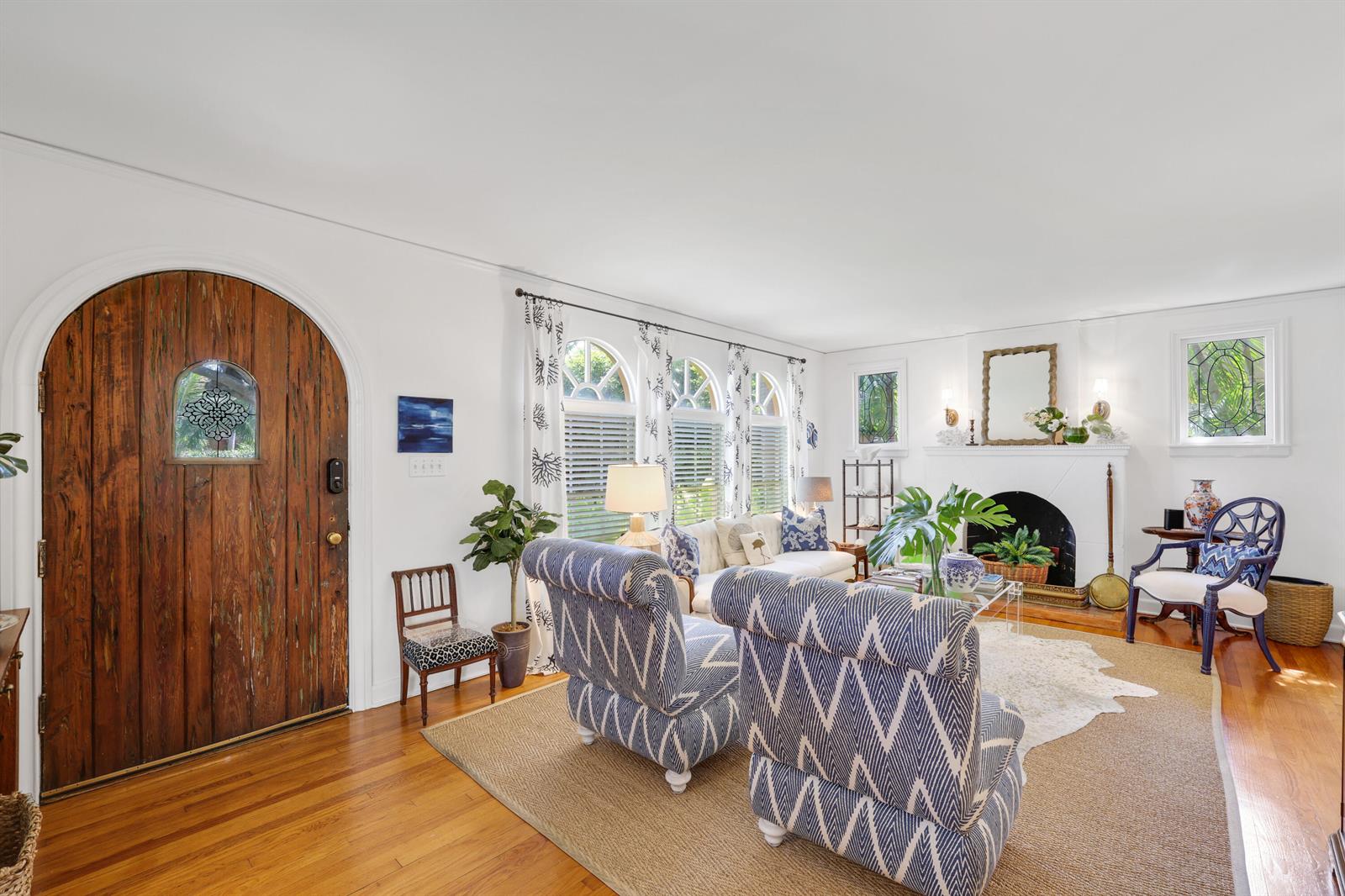 A living room features a wooden arched door, white walls, hardwood floors, and blue furniture — 325 Greymon Drive, West Palm Beach FL 33405, WEST PALM BEACH, FL