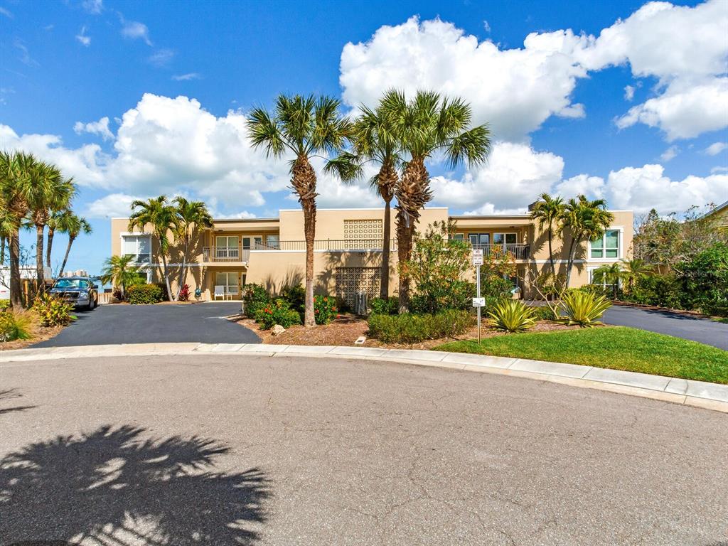 A two-story tan apartment building with palm trees and a paved parking lot in front — 210 DOLPHIN POINT UNIT B, CLEARWATER BEACH, FL