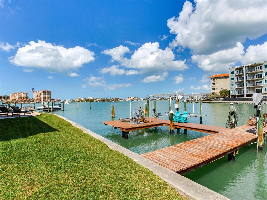 A patio features two wicker chairs with blue cushions flanking a set of blue double doors — 210 DOLPHIN POINT UNIT B, CLEARWATER BEACH, FL