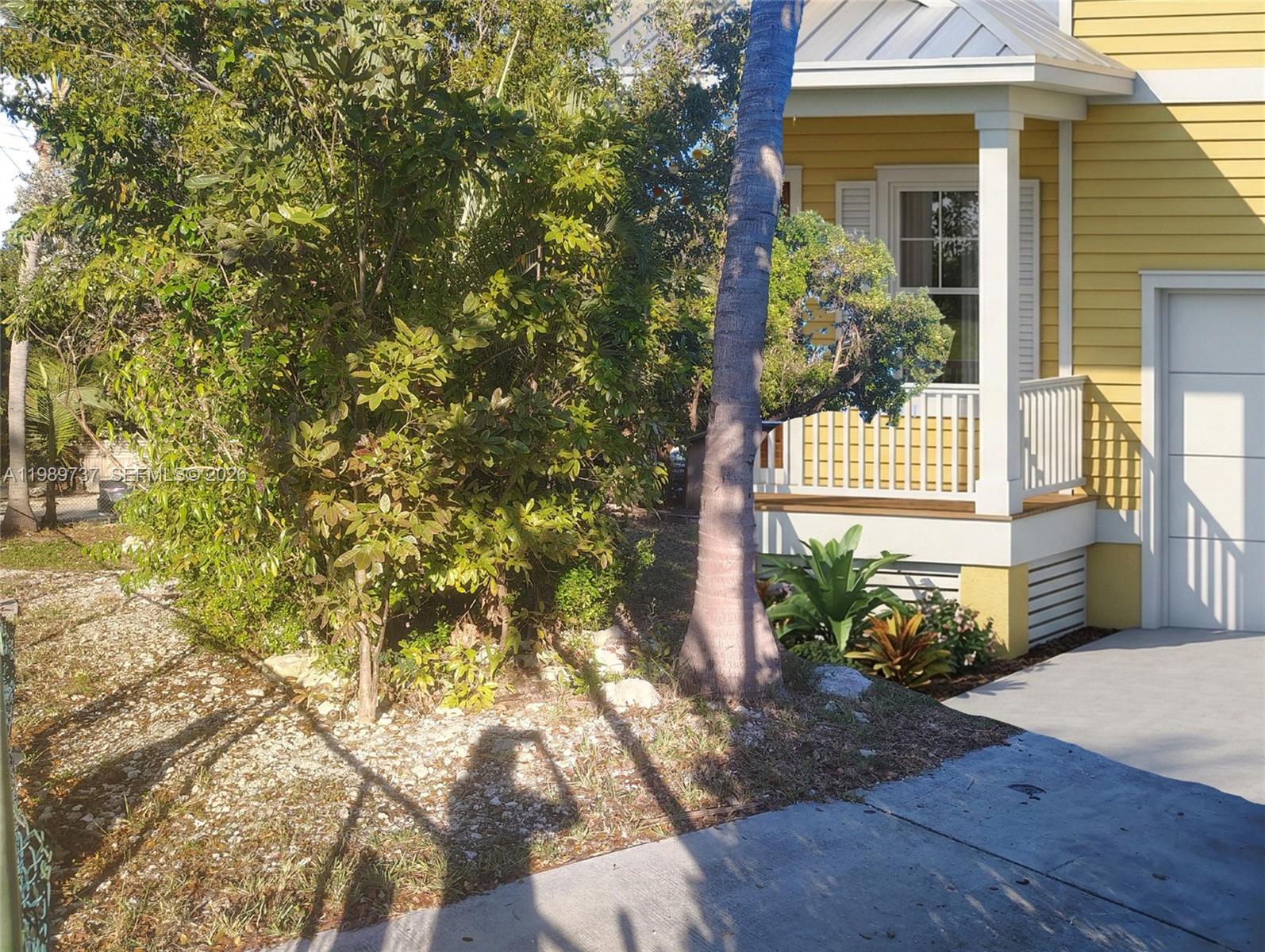 A yellow house with a porch and a palm tree stands next to a driveway — 2330 Staples ave, Key West FL 33040, KEY WEST, FL