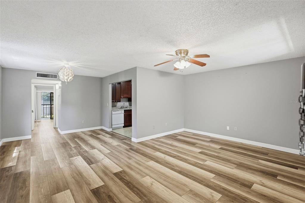 An open-concept living area with light gray walls, wood-look flooring, and a ceiling fan — 11709 RAINTREE VILLAGE BOULEVARD UNIT C, TEMPLE TERRACE, FL