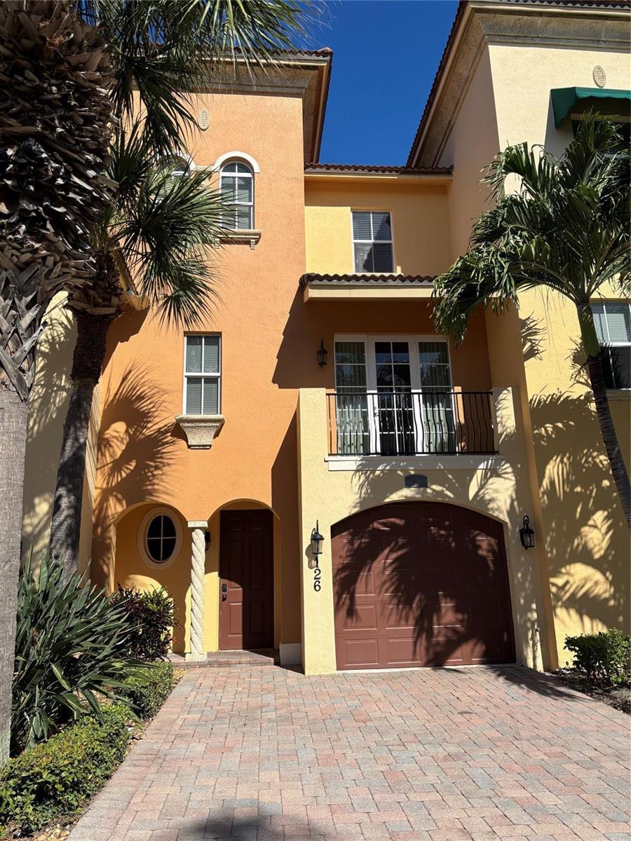 A three-story townhouse with a tan stucco exterior, a garage, and a second-floor balcony — 126 Ocean Bay Drive # 126, Jensen Beach FL 34957, JENSEN BEACH, FL