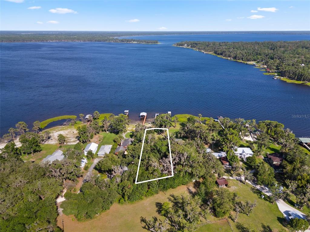 An aerial view shows a wooded, rectangular lot outlined in white near a large lake — 12525 NE 204TH TERRACE, WALDO, FL