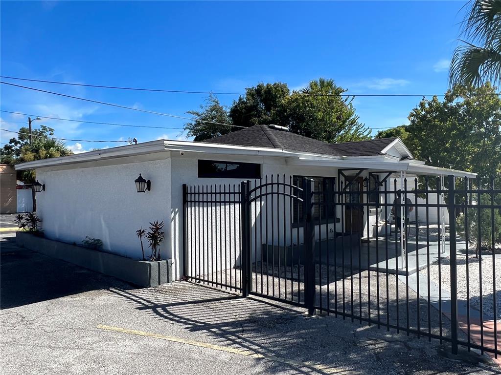 A white stucco house with a black metal fence and a dark shingled roof — 2323 W AILEEN STREET Bldg 2, TAMPA, FL