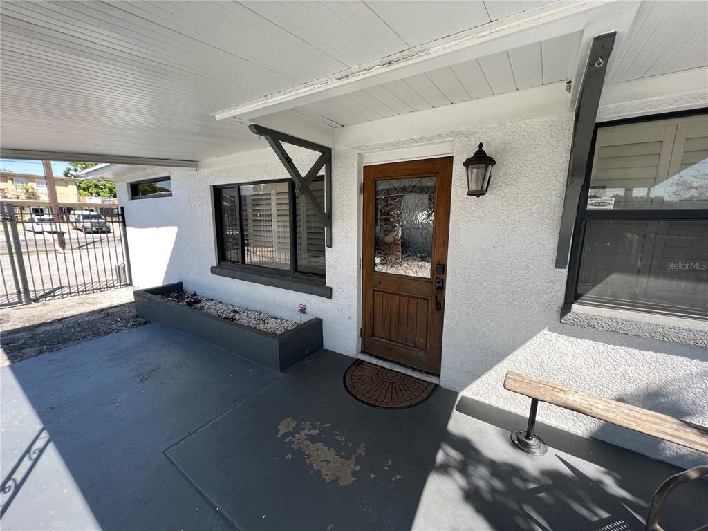 A covered porch features a wooden front door, a planter box, and a bench — 2323 W AILEEN STREET Bldg 2, TAMPA, FL