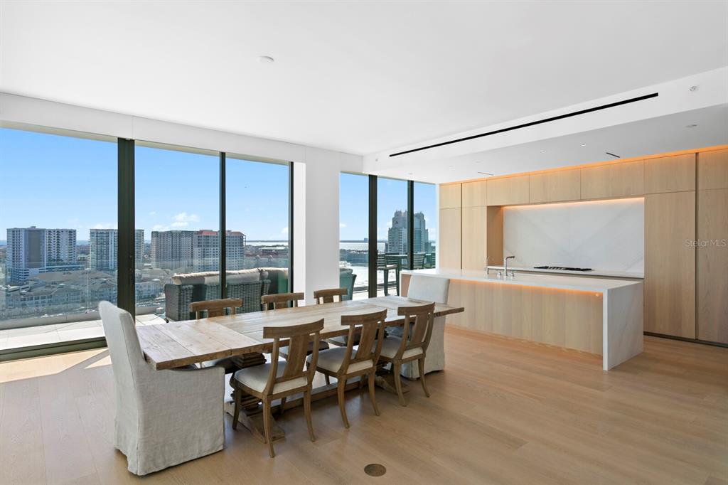 A modern dining area and kitchen with light wood cabinetry, a large island, and floor-to-ceiling windows — 1000 WATER STREET UNIT 1502, TAMPA, FL