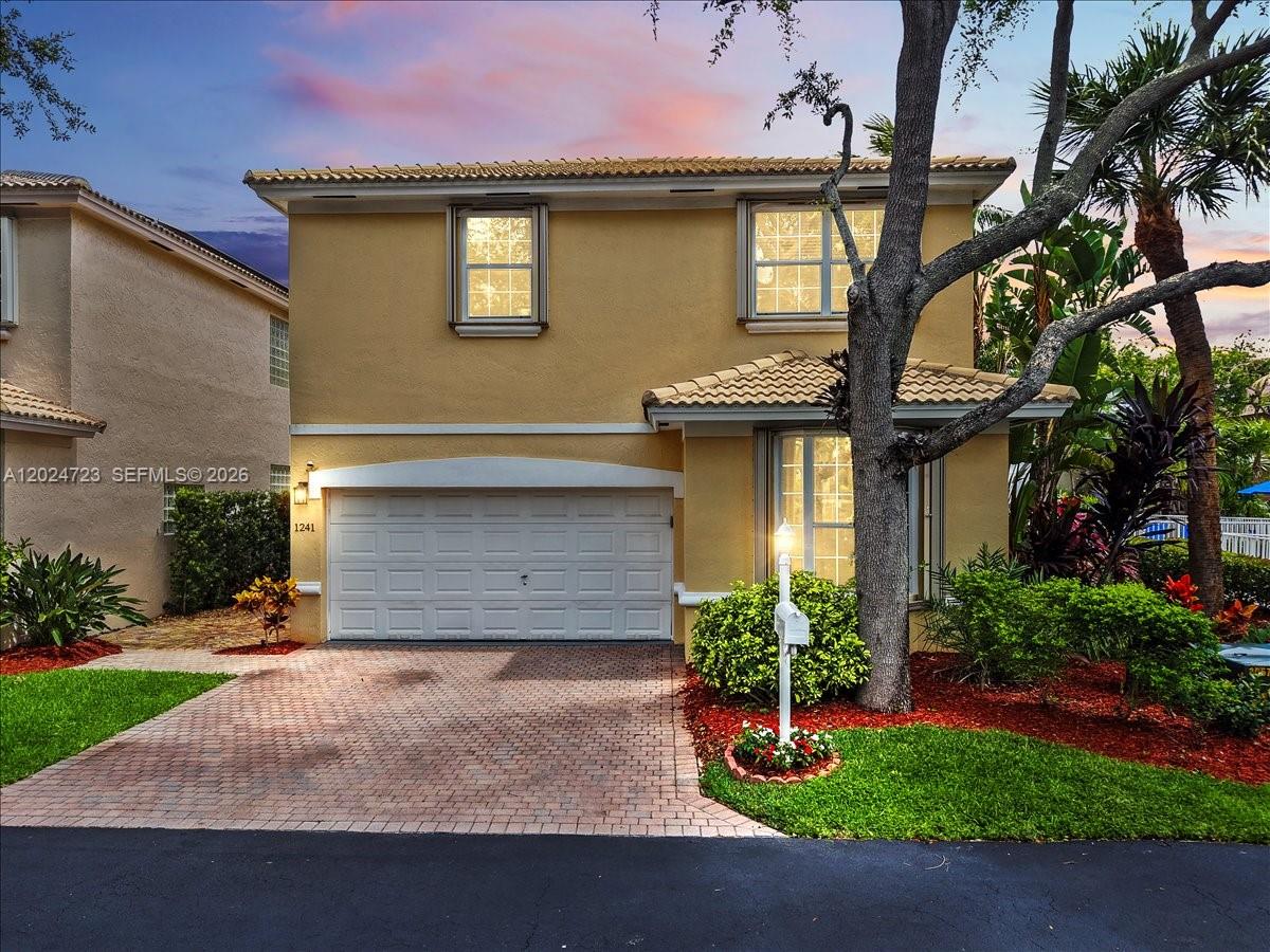 A two-story yellow stucco house features a white garage door and a brick driveway — 1241 Grant St, Hollywood FL 33019, HOLLYWOOD, FL