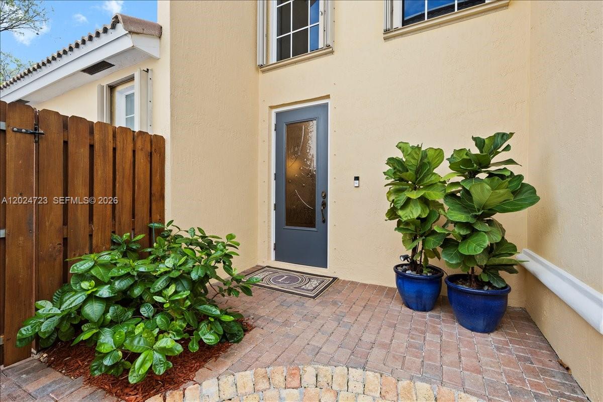 The entrance features a gray door, brick patio, two potted plants, and a wooden fence — 1241 Grant St, Hollywood FL 33019, HOLLYWOOD, FL