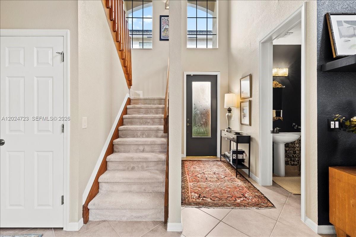 An entryway features a carpeted staircase, a dark front door, and a tiled floor — 1241 Grant St, Hollywood FL 33019, HOLLYWOOD, FL