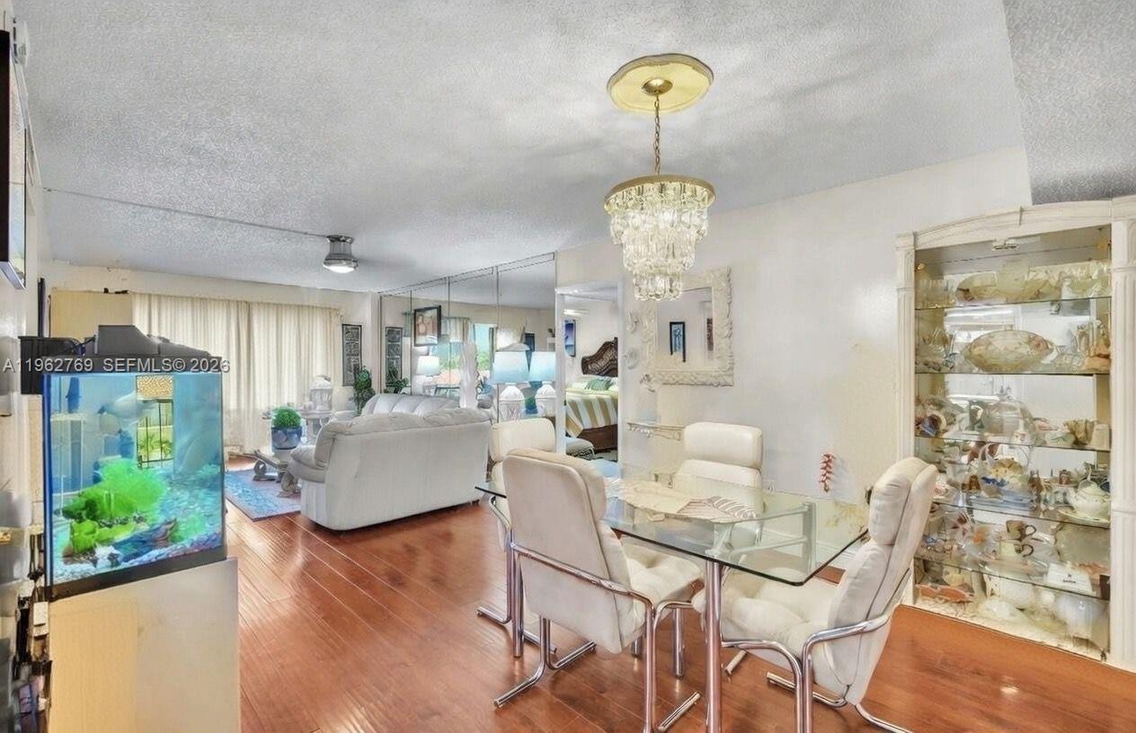 A dining area with a glass table and chandelier sits adjacent to a living room — 4160 Inverrary Dr # 308, Lauderhill FL 33319, LAUDERHILL, FL
