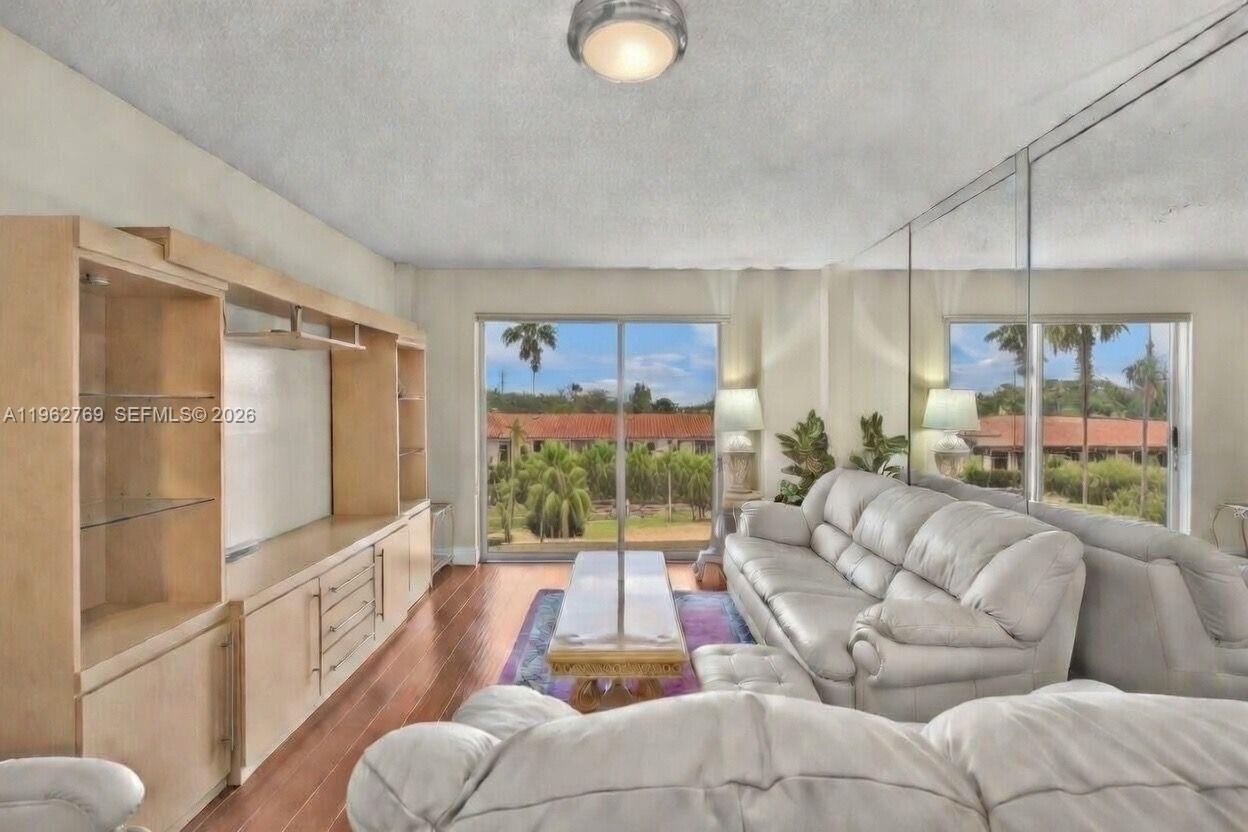 A living room features a light wood entertainment center, white leather sofa, and mirrored walls — 4160 Inverrary Dr # 308, Lauderhill FL 33319, LAUDERHILL, FL